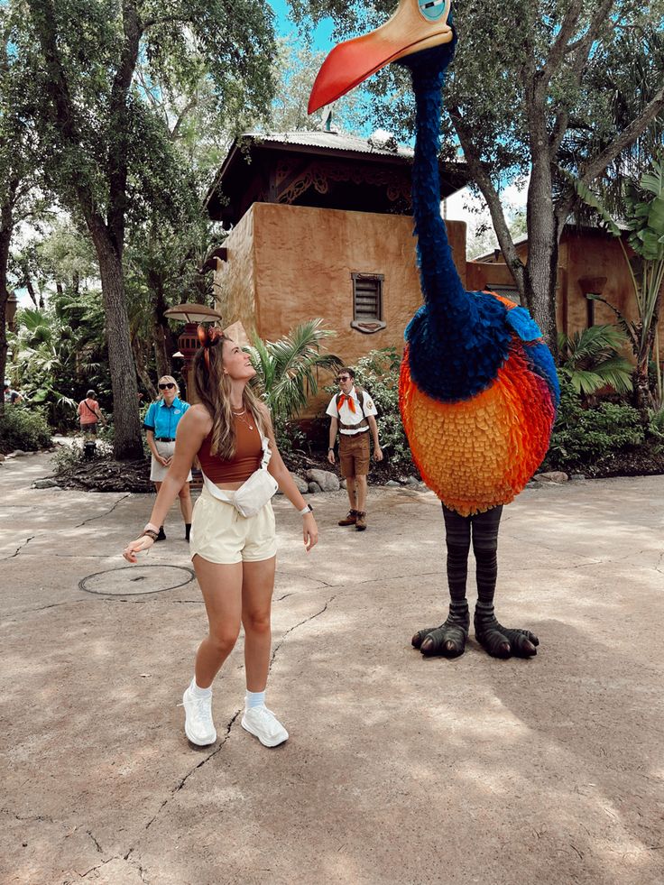 a woman standing next to an ostrich statue