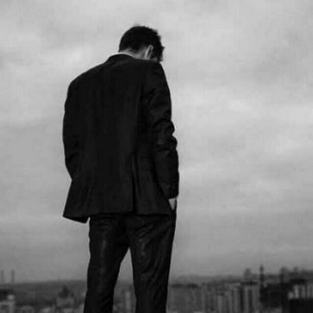 a man in a suit standing on top of a building looking out at the city