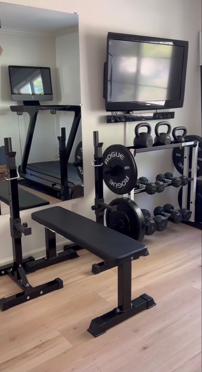 there is a gym with equipment in the room and a television set on the wall