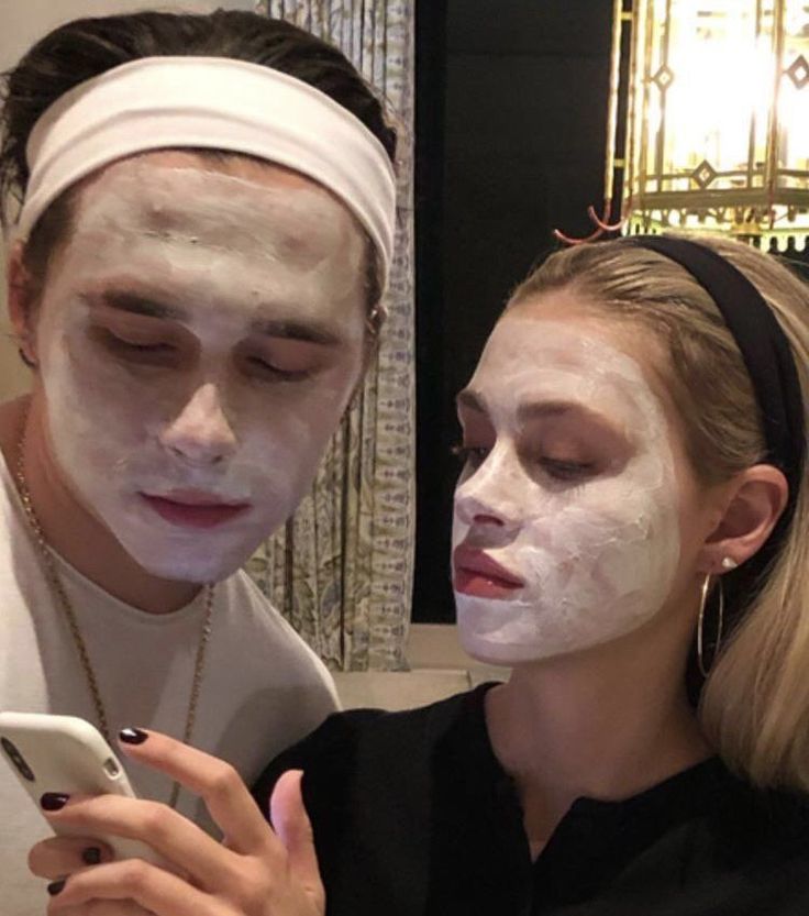 a man and woman with facial masks on looking at a cell phone