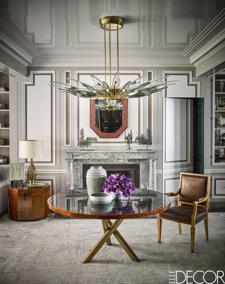 a living room filled with furniture and a fire place under a chandelier above a fireplace