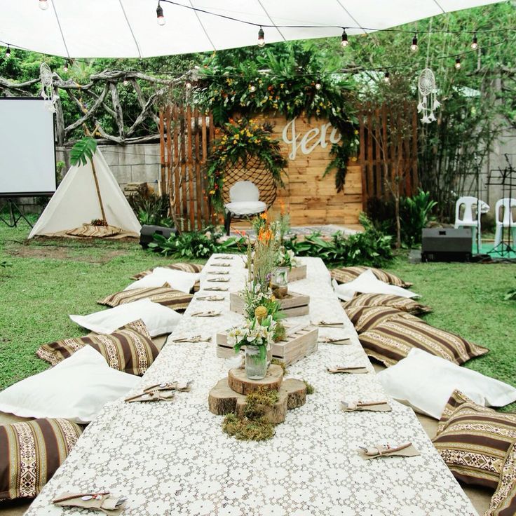 an outdoor dining table set up with pillows and place settings for people to sit at