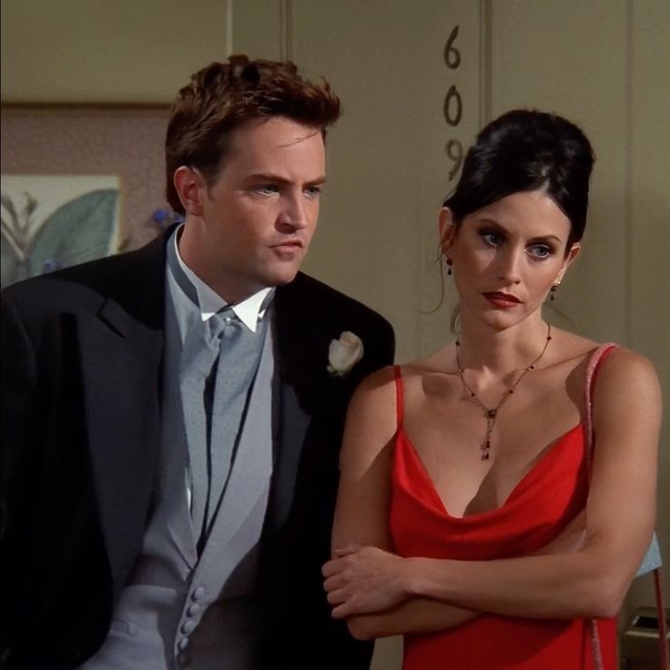 a woman in a red dress standing next to a man in a suit