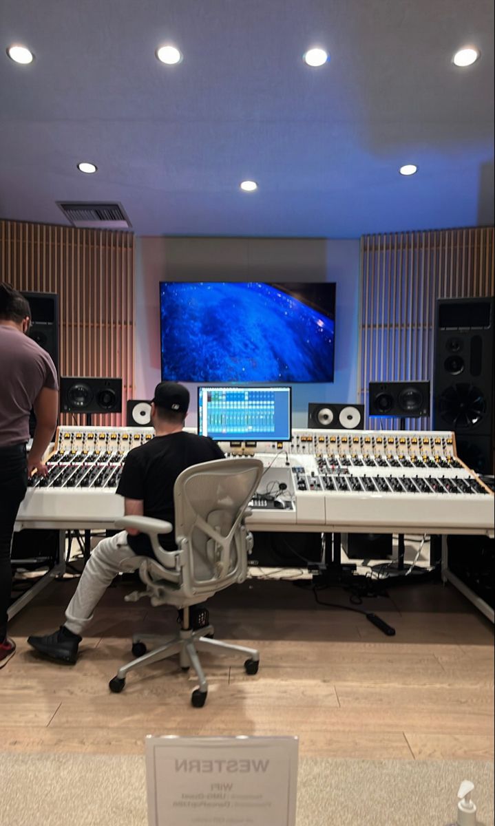 two men sitting in front of sound mixing equipment