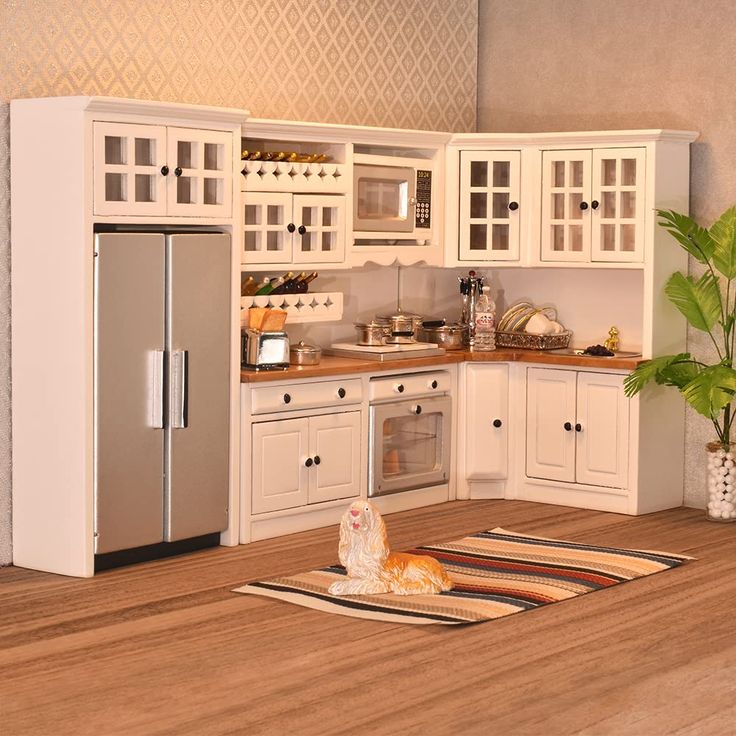 a model kitchen with white cabinets and wood flooring, including a silver refrigerator freezer