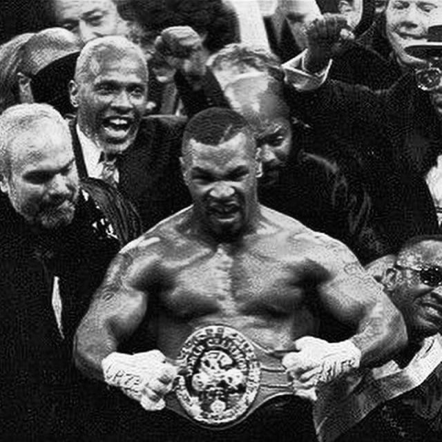 the professional boxer is surrounded by his fans as he poses with his belt in front of him