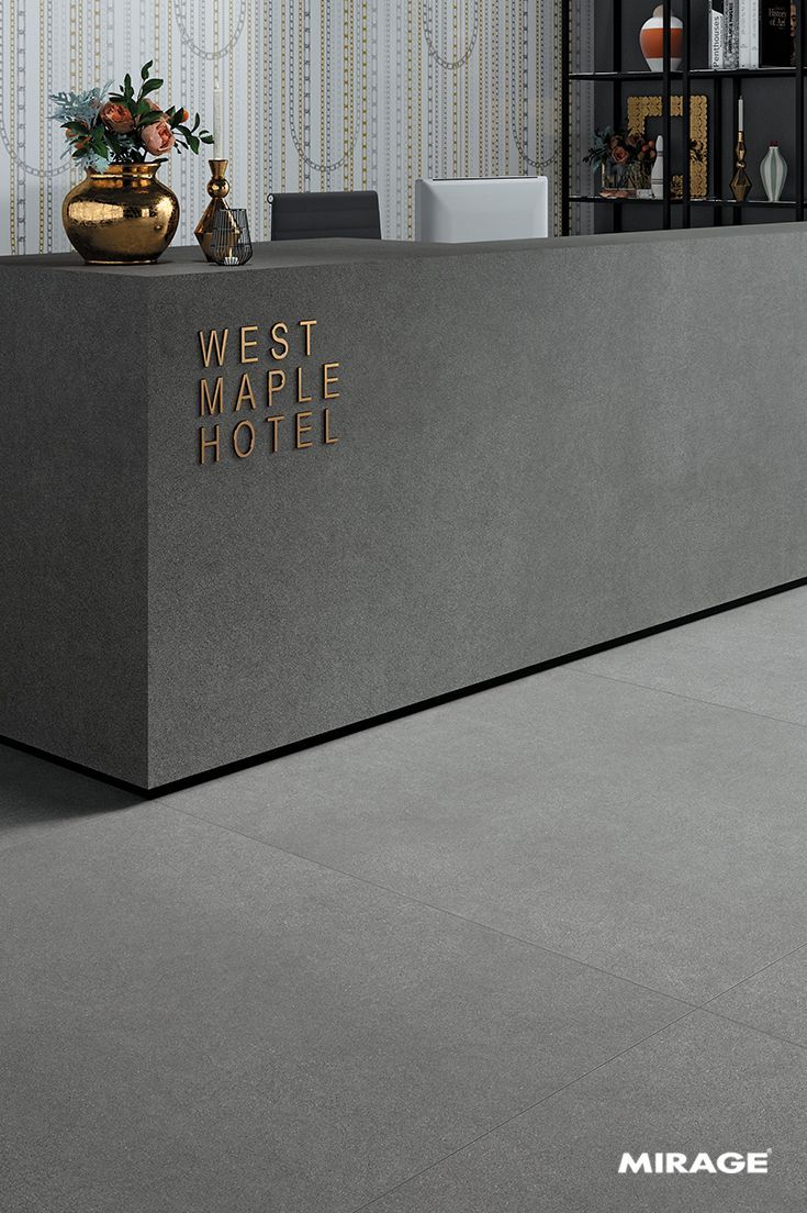 the front desk of a hotel with gold lettering on it's wall and vases