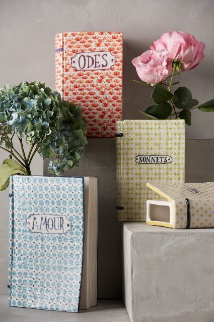 three books are stacked on top of each other with flowers in vases next to them