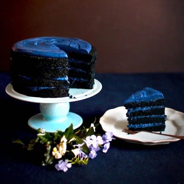 a piece of blue cake sitting on top of a plate next to a slice of cake