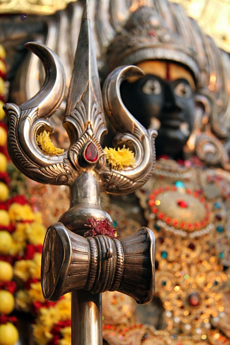 an ornate metal sculpture with two faces on it's head and arms, surrounded by other decorations