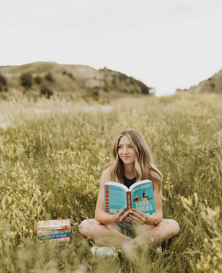 a woman sitting in the grass reading a book