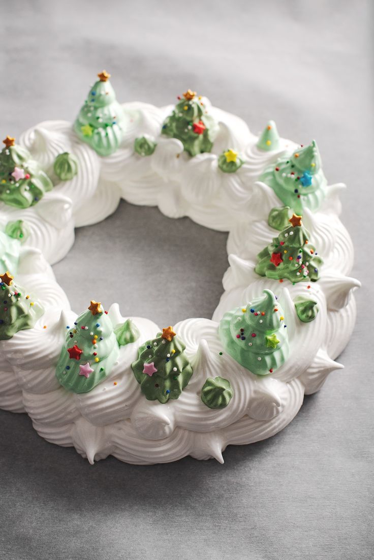 a christmas pavlova wreath made with white frosting and green decorations