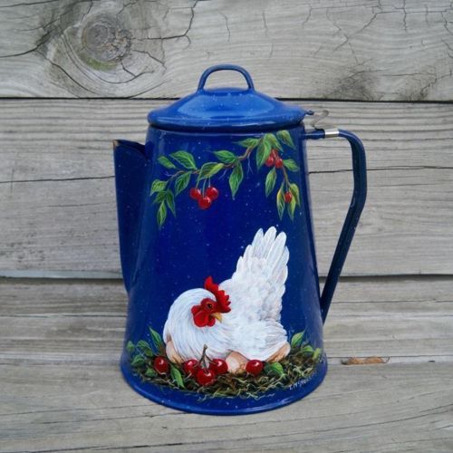 a blue pitcher with a rooster painted on the side and holly garland around it's neck