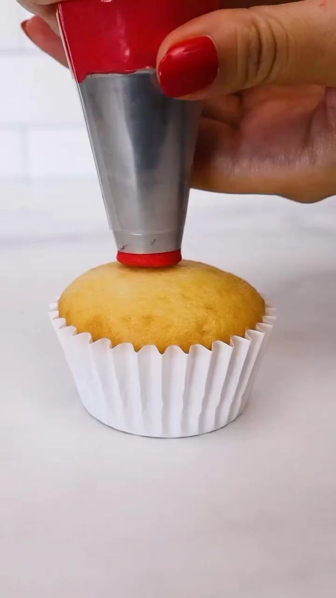 a cupcake being dunked into a muffin tin by a woman's hand