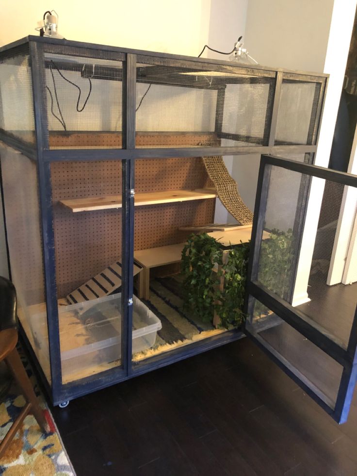 a large cage with plants inside of it on the floor in front of a door