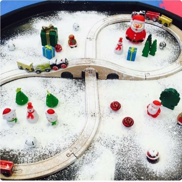 a toy train set in the snow with santa and other toys on it's tracks