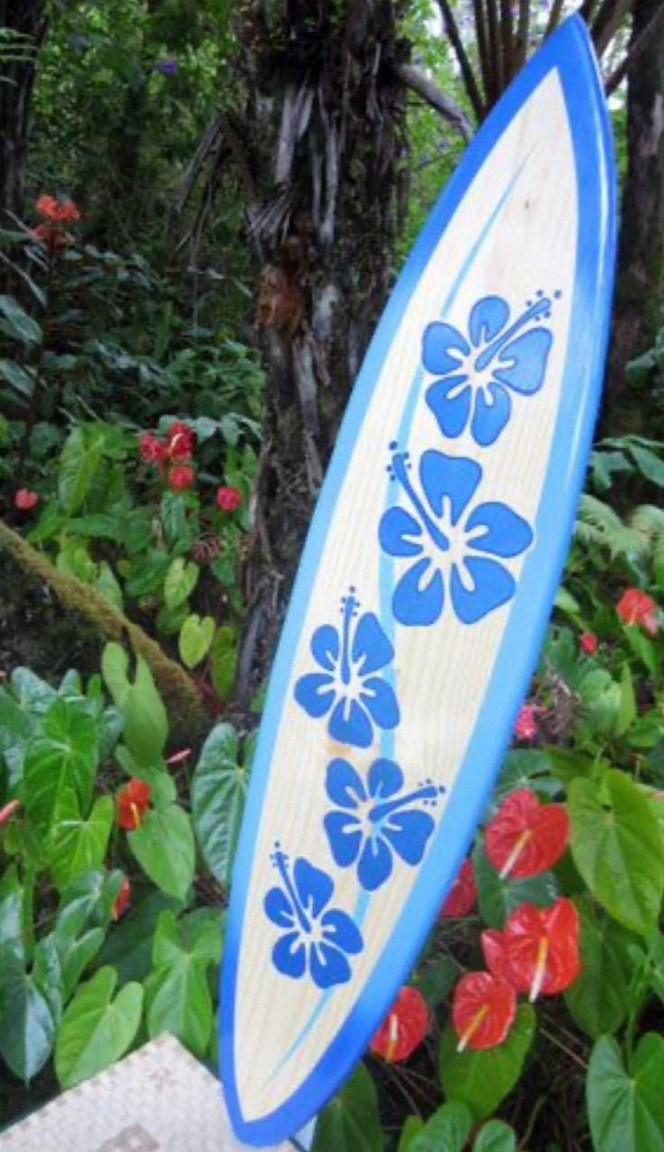 a blue and white surfboard sitting on top of a wooden table next to flowers