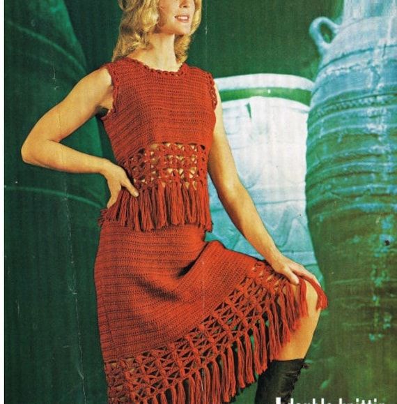 a woman in a red crocheted dress and black boots posing for a photo