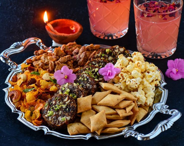 a platter filled with different types of food next to two glasses full of water