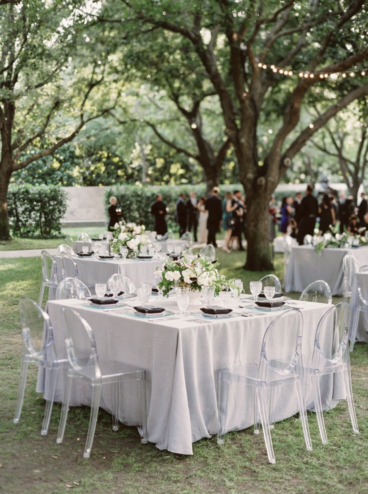 an outdoor wedding reception with white table cloths and clear chairs