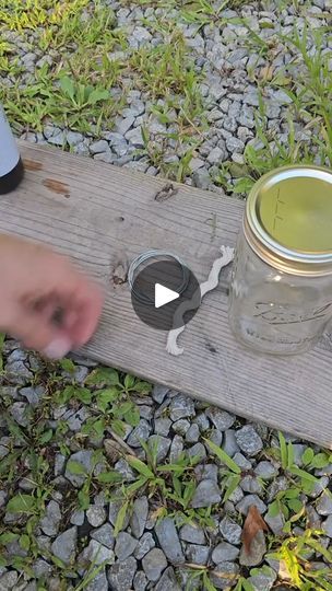 a person holding a knife next to a mason jar on top of a wooden plank