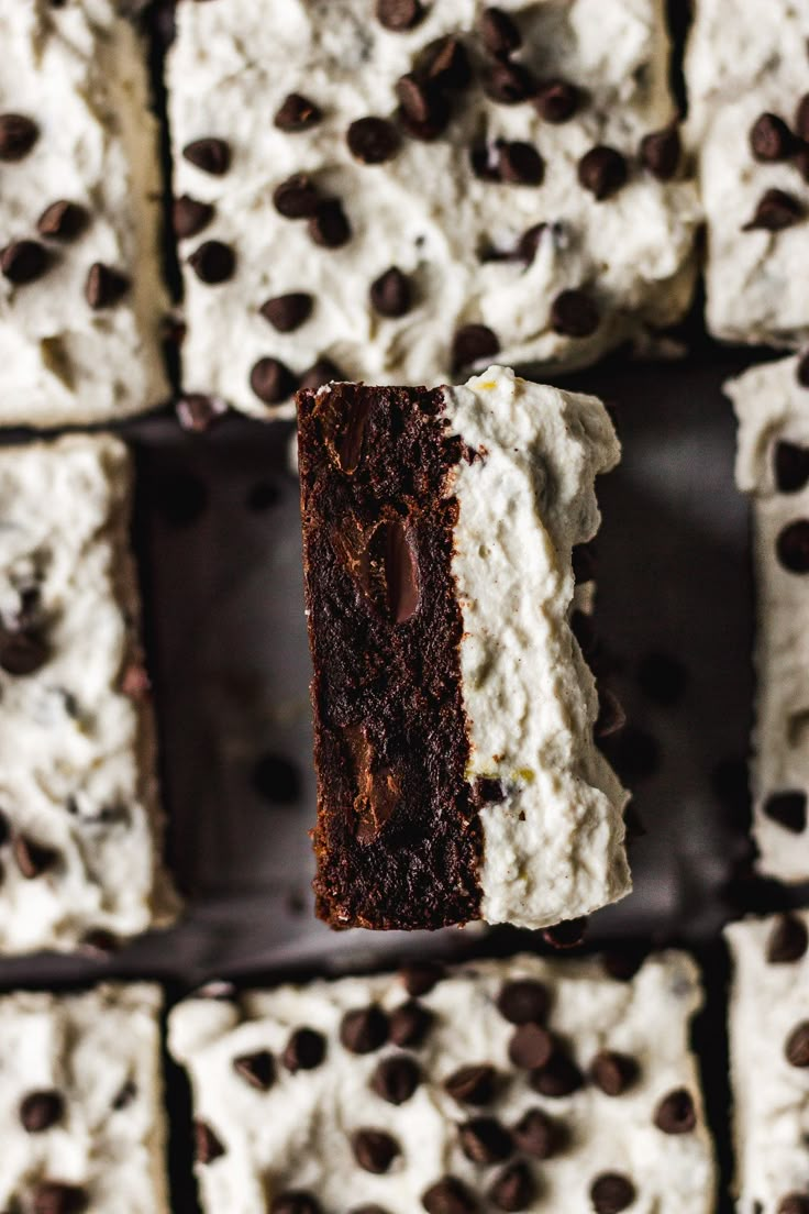 a piece of chocolate cake with white frosting and chocolate chips