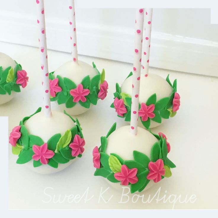 four cake pops decorated with flowers and candles