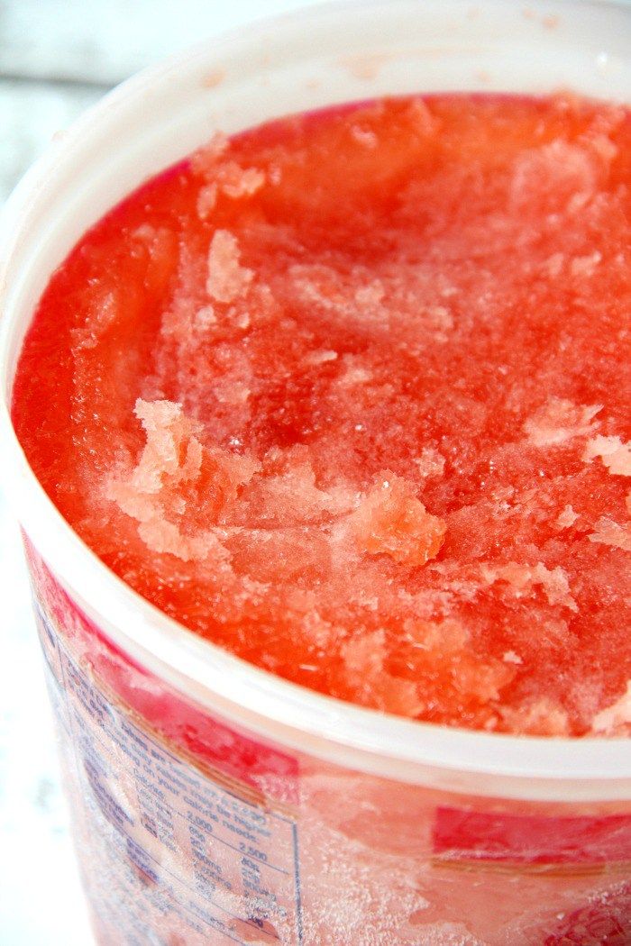 a plastic cup filled with watermelon sitting on top of a white countertop