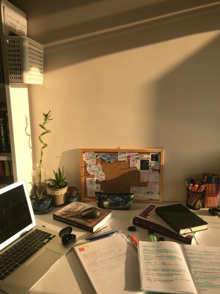 an open laptop computer sitting on top of a desk next to a pile of books