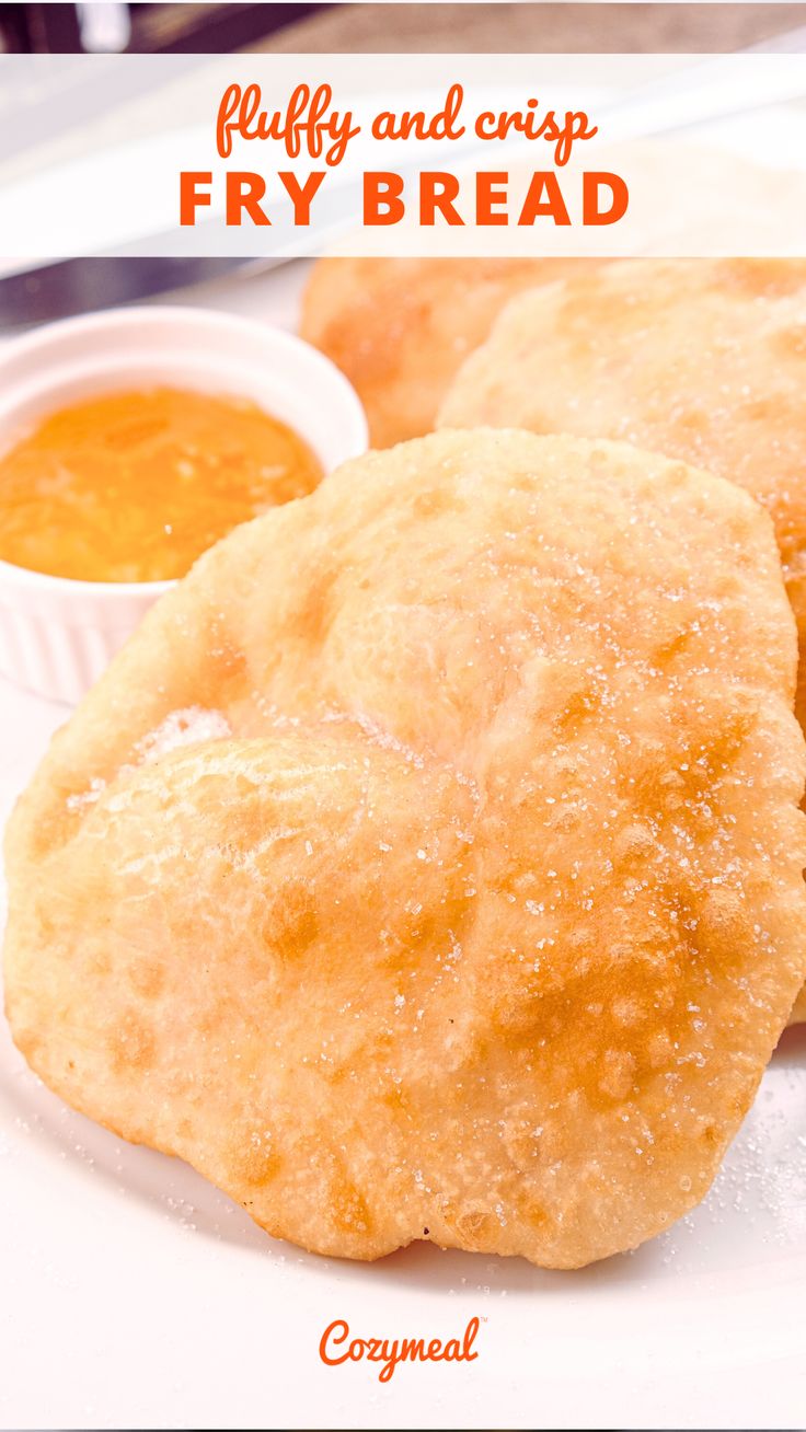 two puffy and crisp fry breads on a plate with dipping sauce in the background