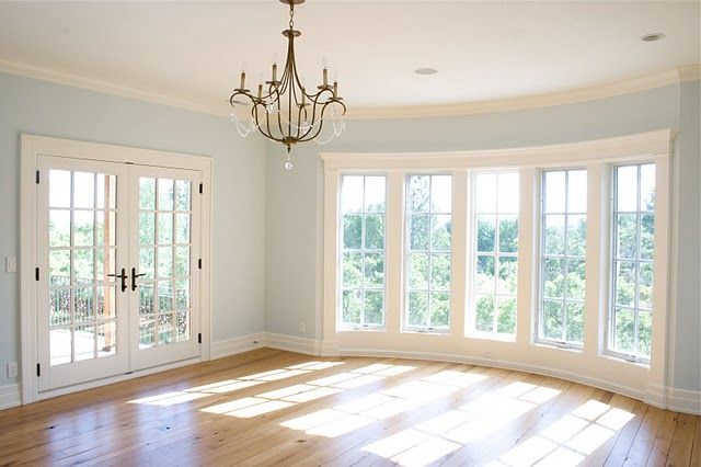 an empty room with two french doors and a chandelier