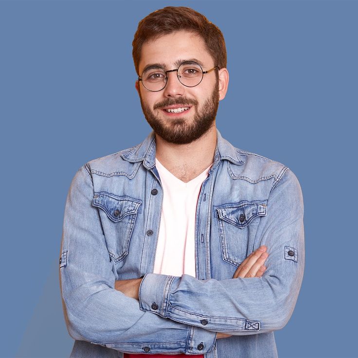 a man with glasses and a beard is standing with his arms crossed in front of him