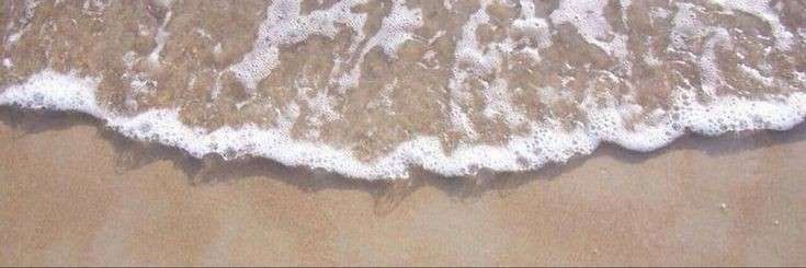 an aerial view of the ocean waves and sand