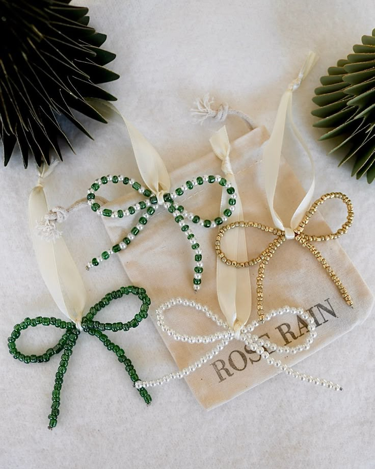 some green and white beads are laying on a piece of cloth next to palm leaves