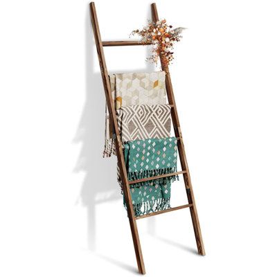 a wooden ladder with blankets hanging from it's sides and flowers on the top