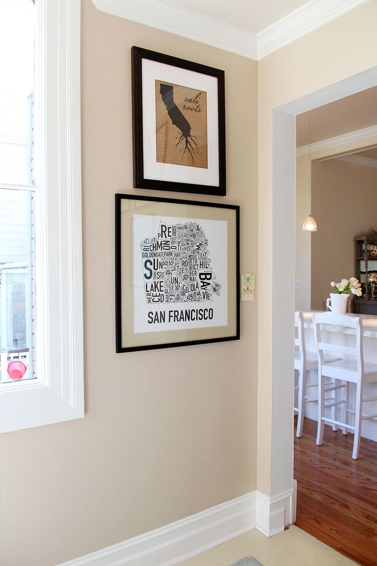 two framed pictures hang on the wall above a dining room table