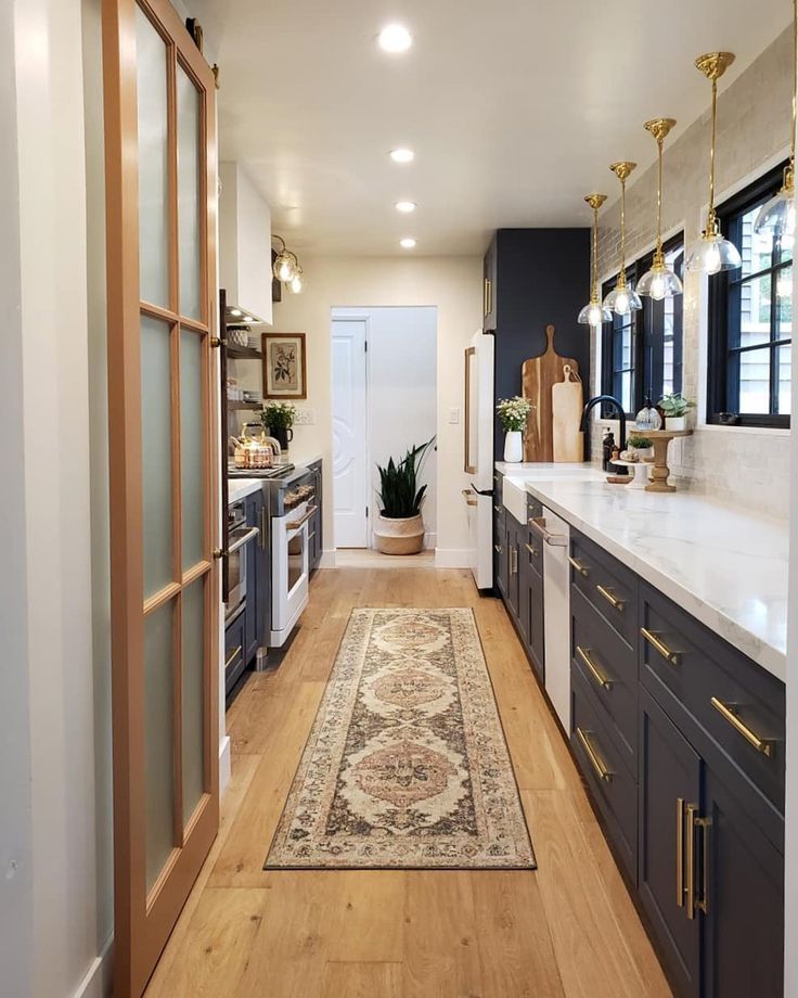 a narrow kitchen with wood floors and white walls, along with an area rug on the floor