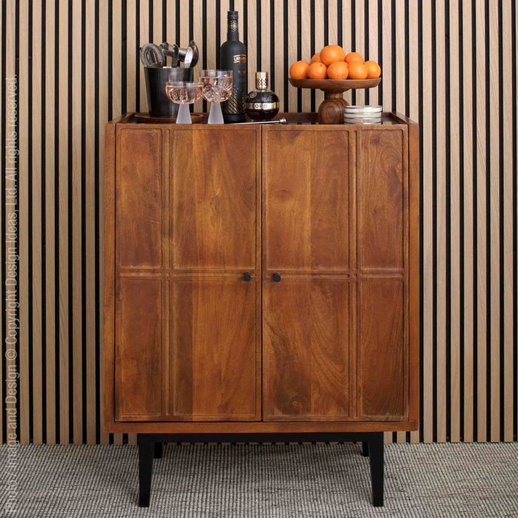 a wooden cabinet sitting in front of a wall with striped walls behind it and oranges on top