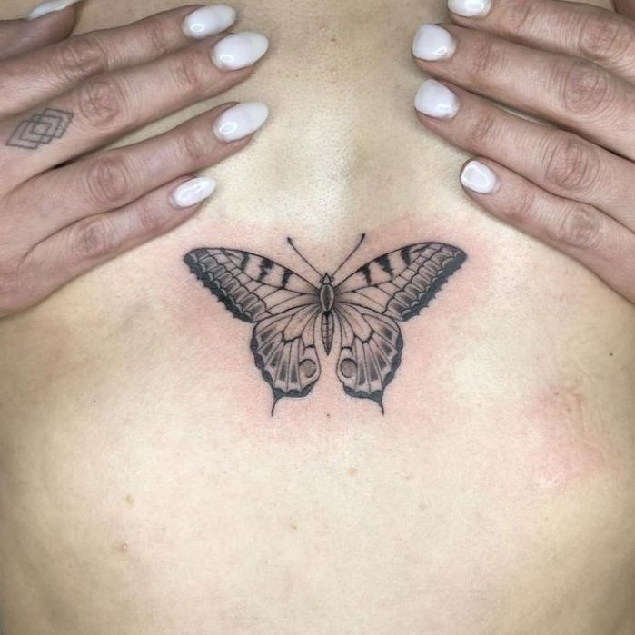 a woman's chest with a butterfly tattoo on her left side ribcage