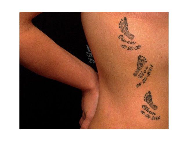 a woman's lower back tattoo with footprints and words on the bottom part of her body