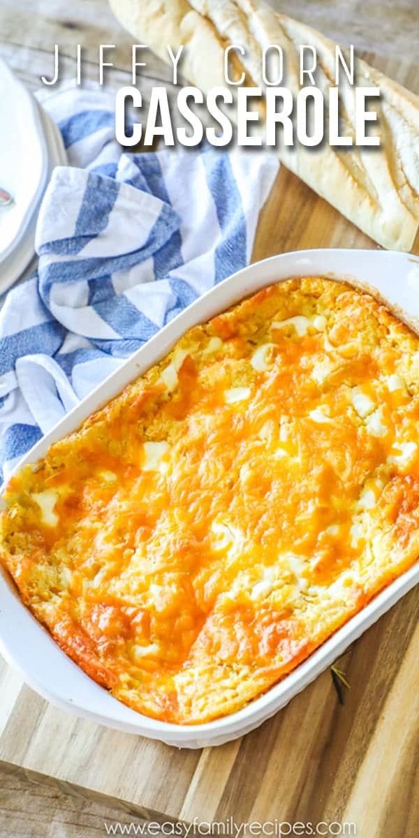 a casserole in a white dish on top of a wooden table next to bread