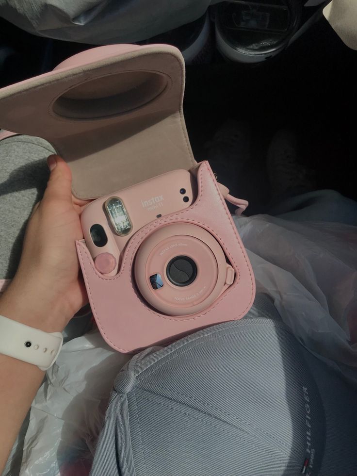 a person holding a pink camera in their hand