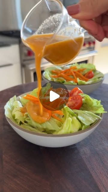 someone pouring dressing into a salad in a bowl with lettuce and carrots