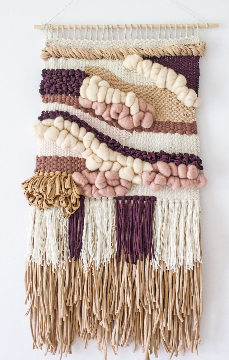 a wall hanging made out of different types of yarns and tassels on a white background