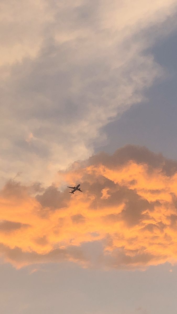 an airplane is flying in the sky at sunset