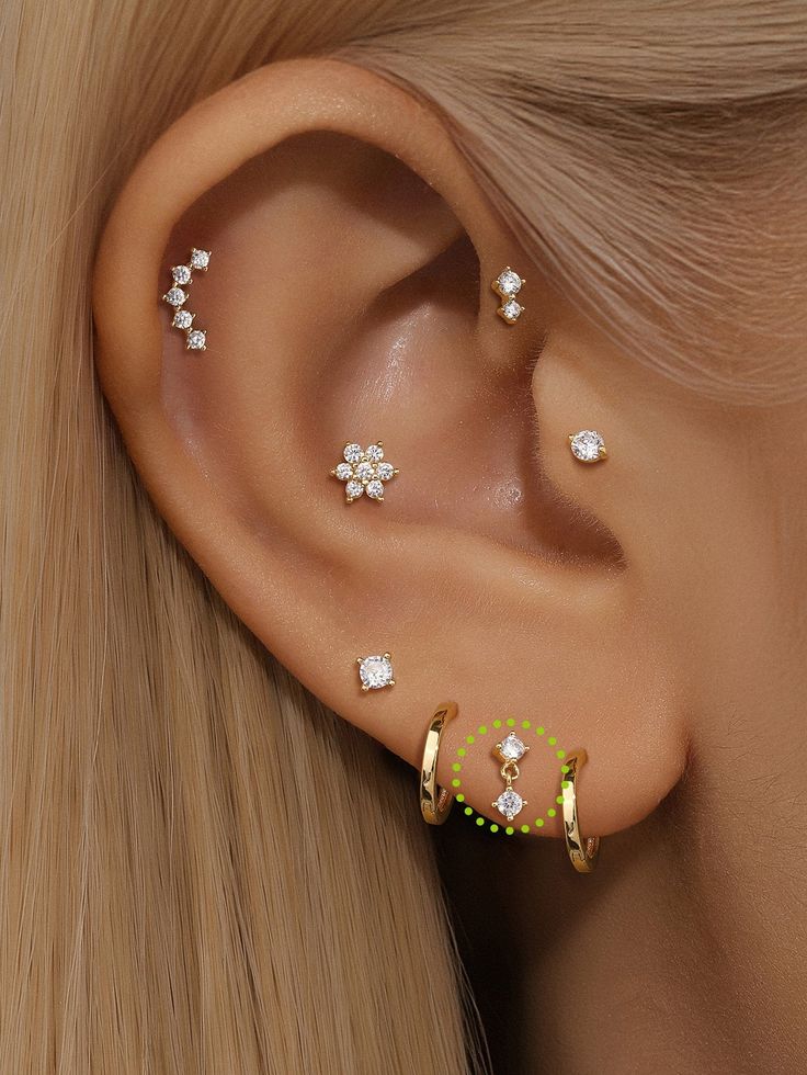 a close up of a woman's ear with three piercings