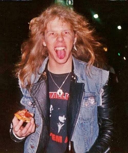 a man with long hair holding a donut and making a funny face while wearing a jean jacket