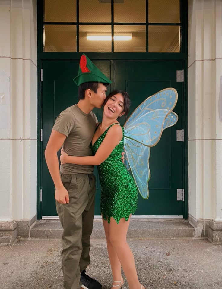 a man and woman dressed up as tinkerbells pose for a photo in front of a green door