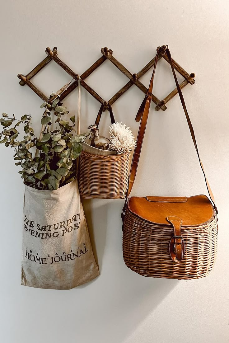 two wicker baskets hanging on the wall with plants in them next to a canvas bag