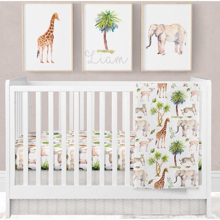 a baby crib with two pictures on the wall and a giraffe blanket